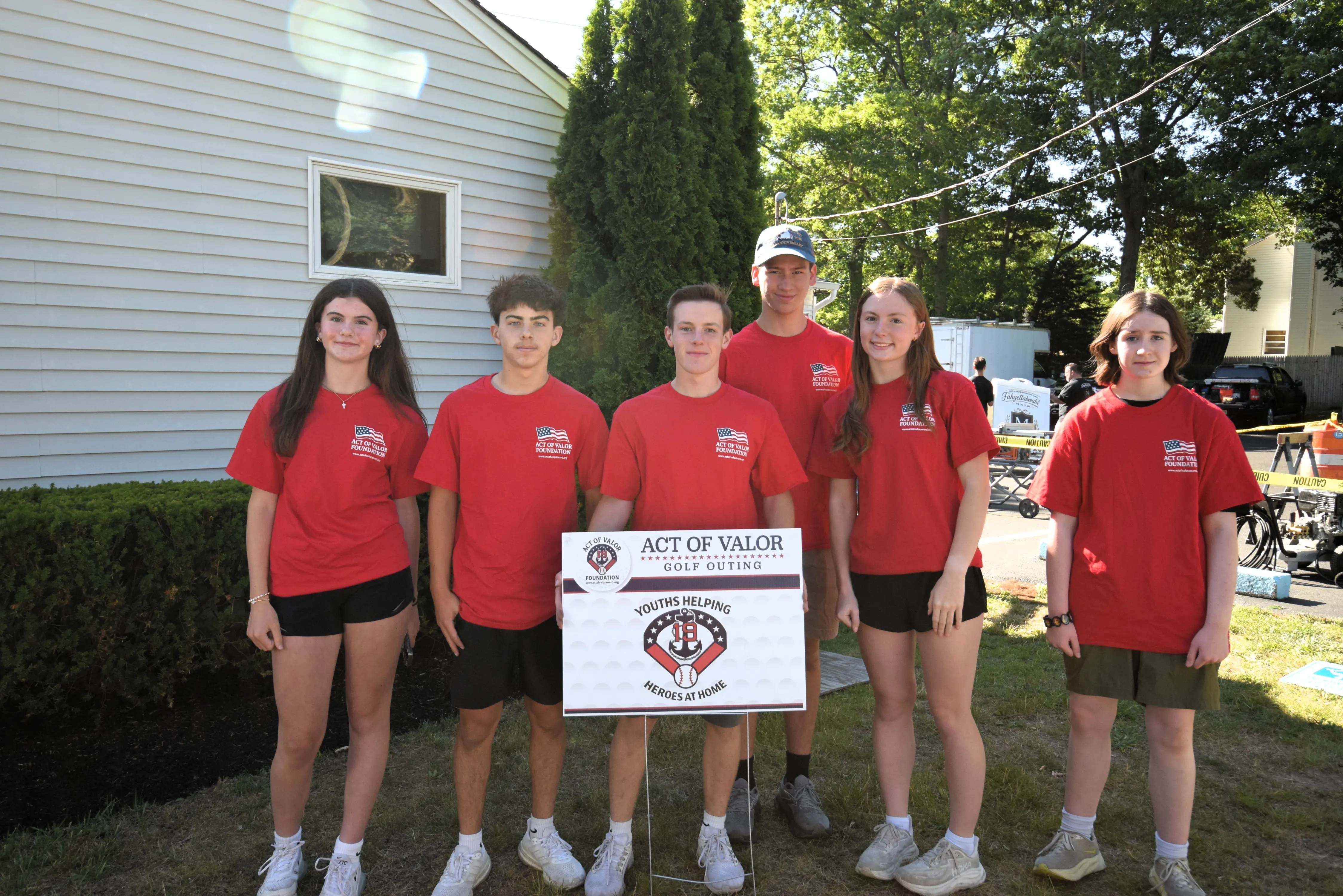 Youth volunteers from the Youths Helping Heroes at Home program holding an Act of Valor Foundation sign