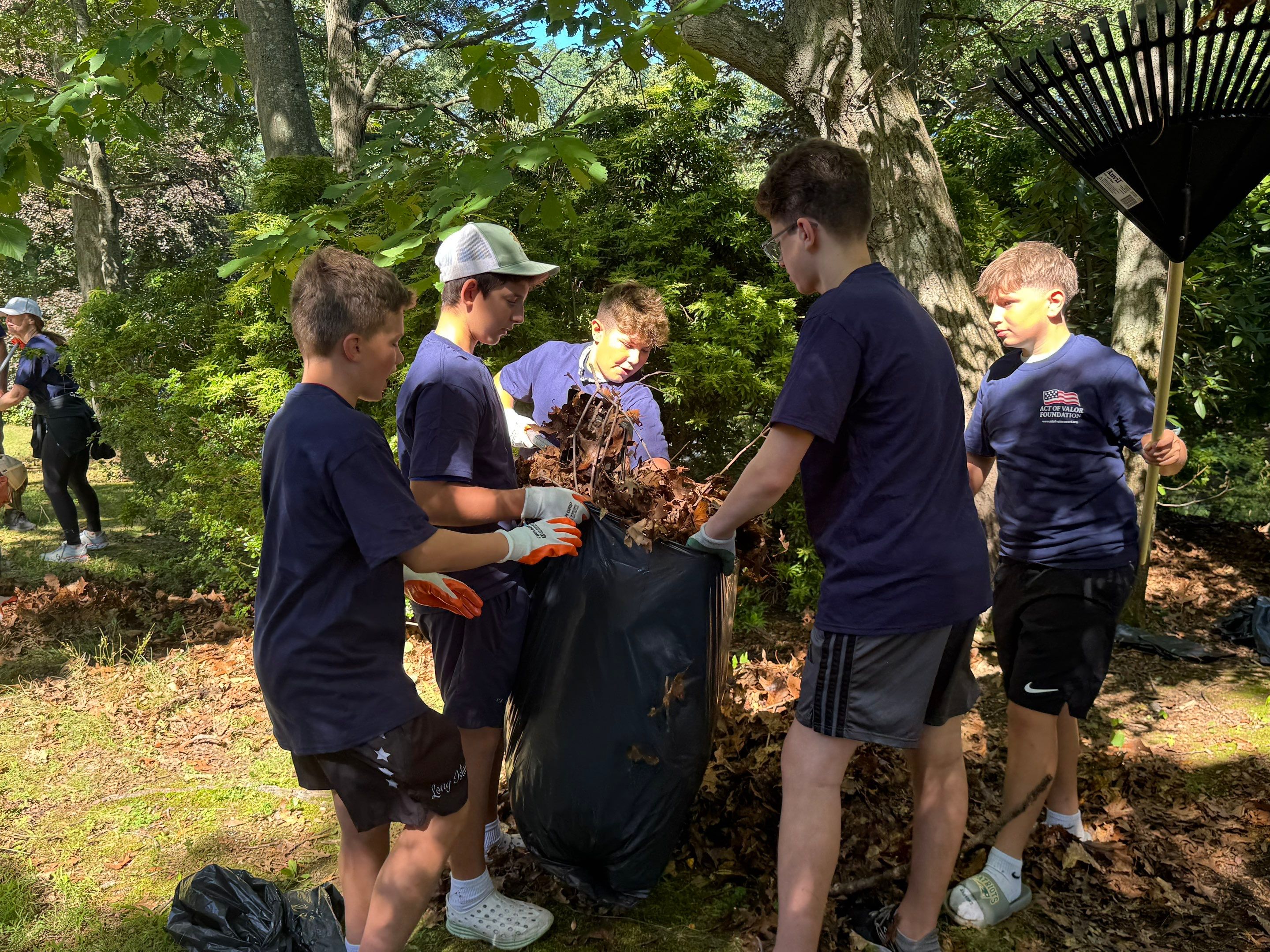 Students bagging leaves together during the veteran yard restoration