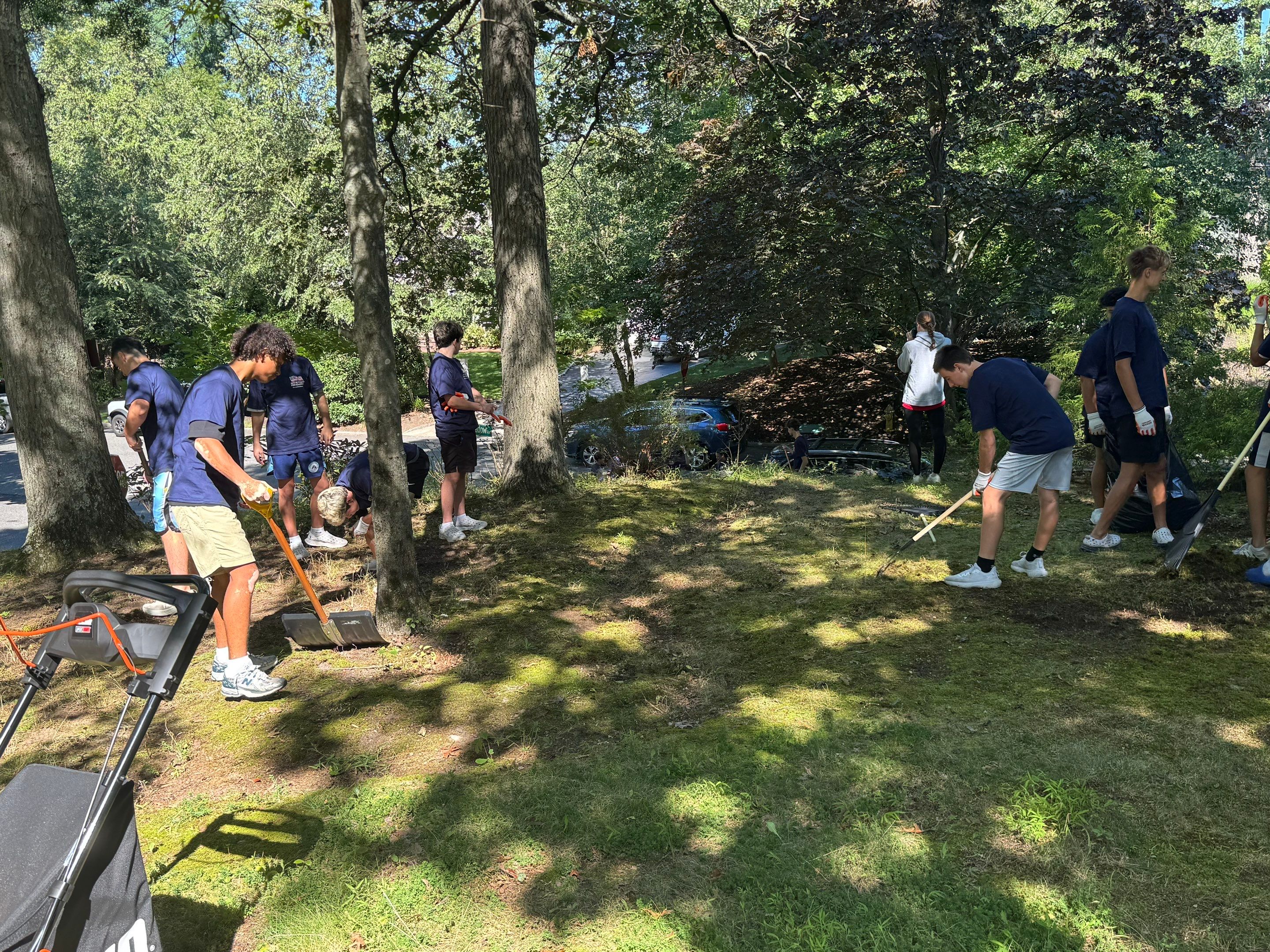 Student volunteers raking and clearing the veteran's yard during the Youths Helping Heroes at Home project